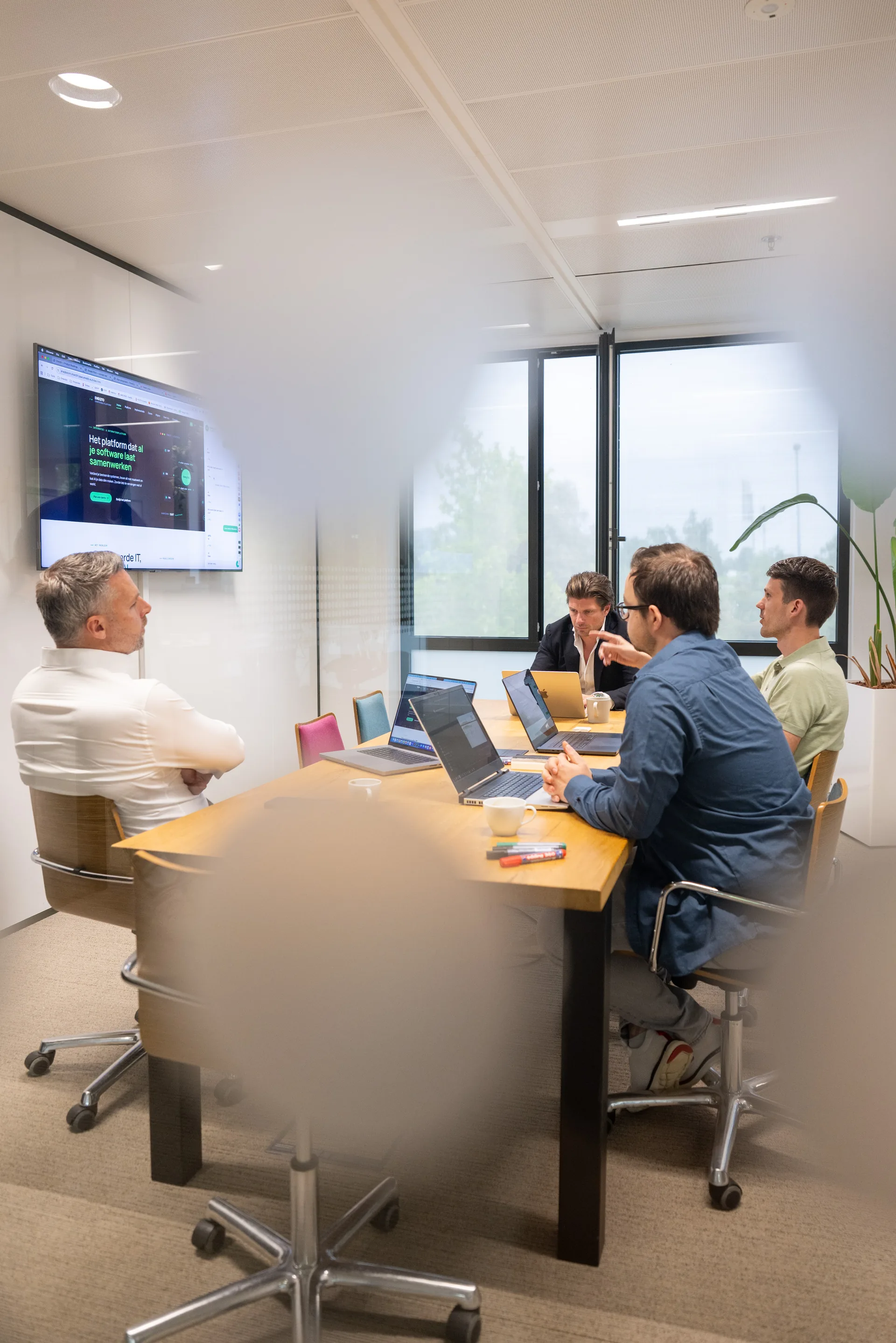 Meeting in een glazen kantoorruimte met vier Emendis-collega's