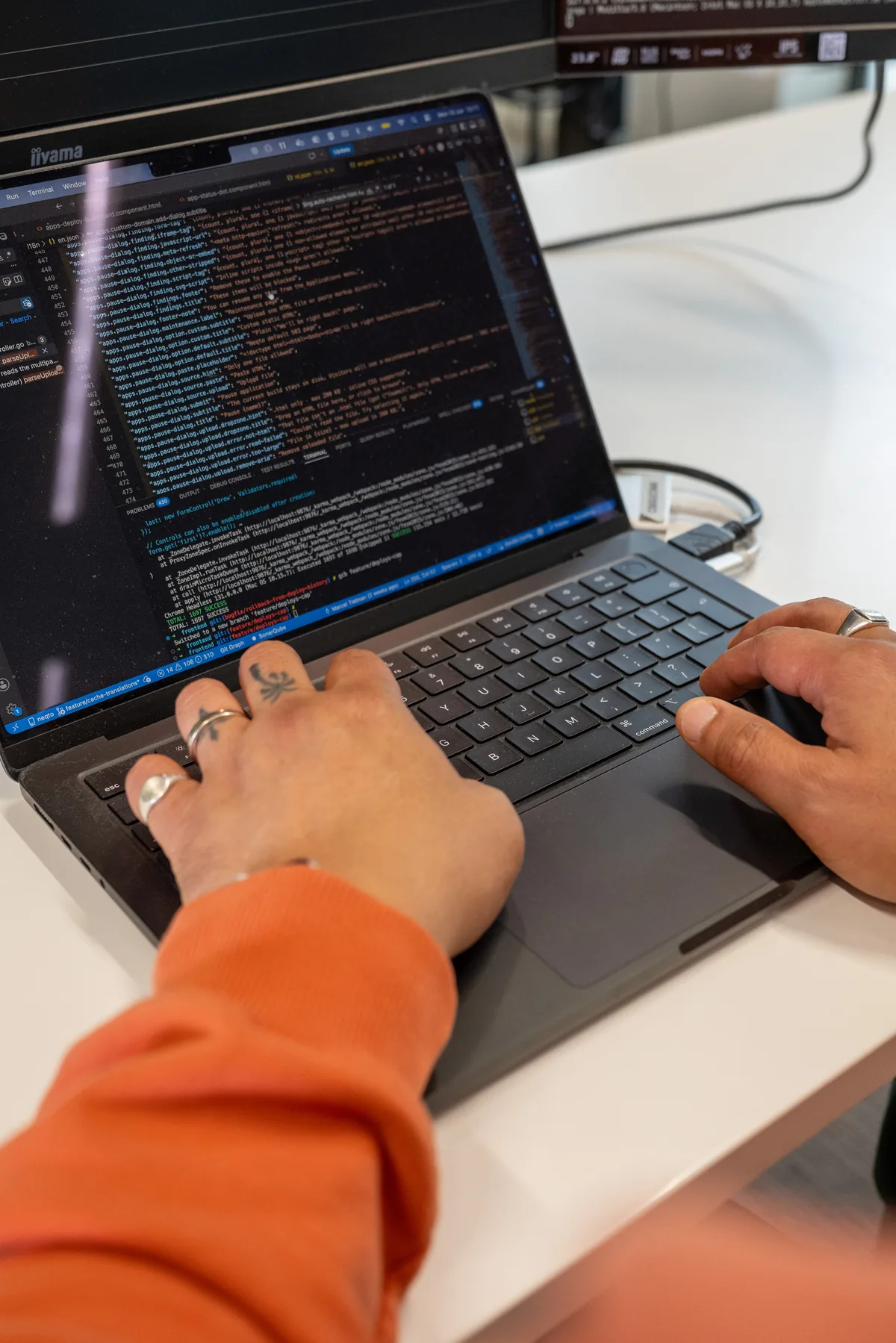 Handen typend op MacBook met code