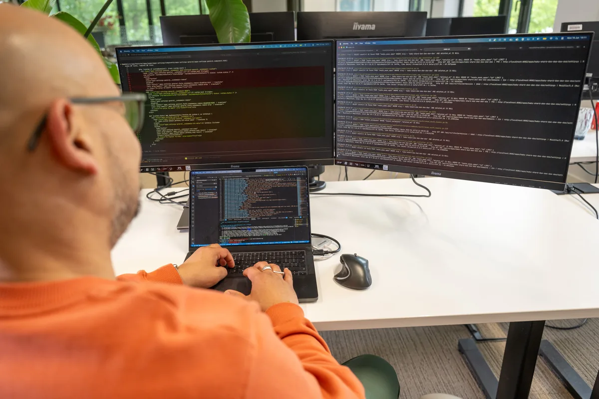 Ontwikkelaar met dubbele monitors bekijkt code